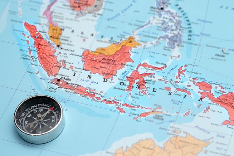 Compass on a map pointing at Indonesia and planning a travel destination