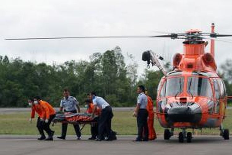 Petugas Basarnas membawa jenazah dari helikopter menuju ambulans di Posko Utama Pecarian Pesawat AirAsia QZ8501, Lanud Iskandar, Pangkalan Bun, Kalteng, Rabu (31/12/2014). Dua dari tujuh jenazah yang telah ditemukan dibawa ke posko untuk kemudian diidentifikasi di RSUD Sultan Imanudin. TRIBUN NEWS / DANY PERMANA