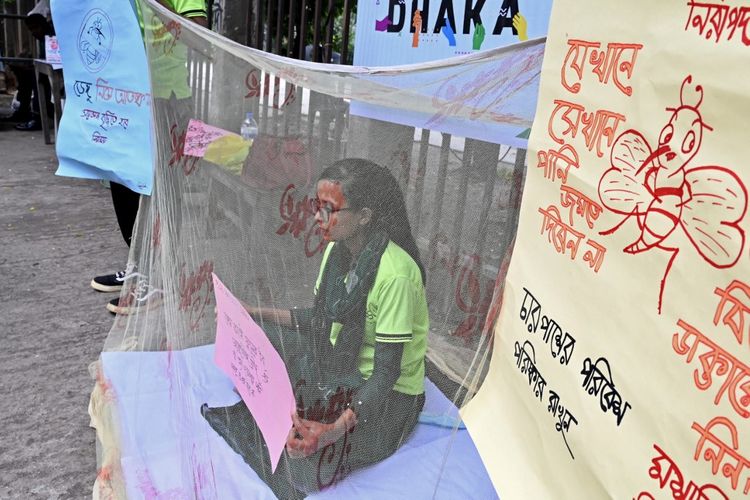 Seorang anak perempuan memegang sebuah poster sambil duduk di dalam kelambu dalam sebuah kampanye kesadaran terhadap penyakit yang ditularkan oleh nyamuk, di Dhaka, Bangladesh, pada 14 Agustus 2023. Lebih dari 1.000 orang di Bangladesh telah meninggal karena demam berdarah sejak awal tahun ini. 