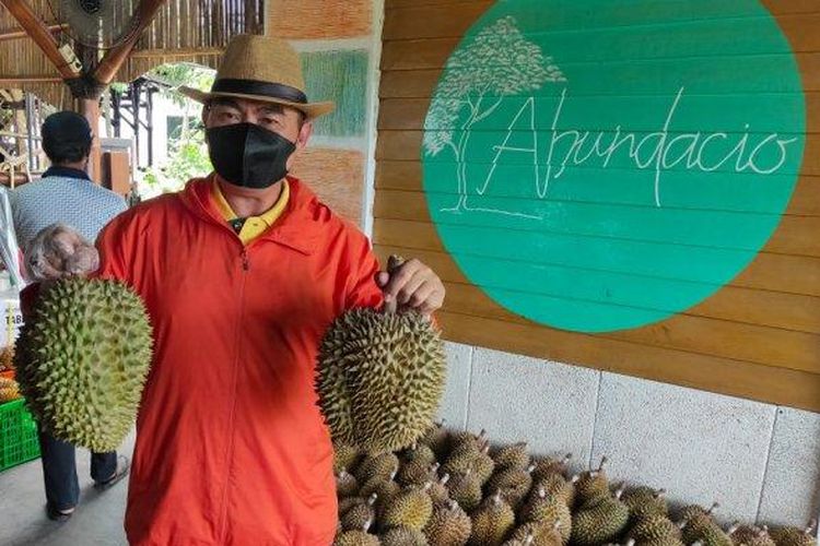 Abah Anton memegang durian hasil panen dari kebunnya. 