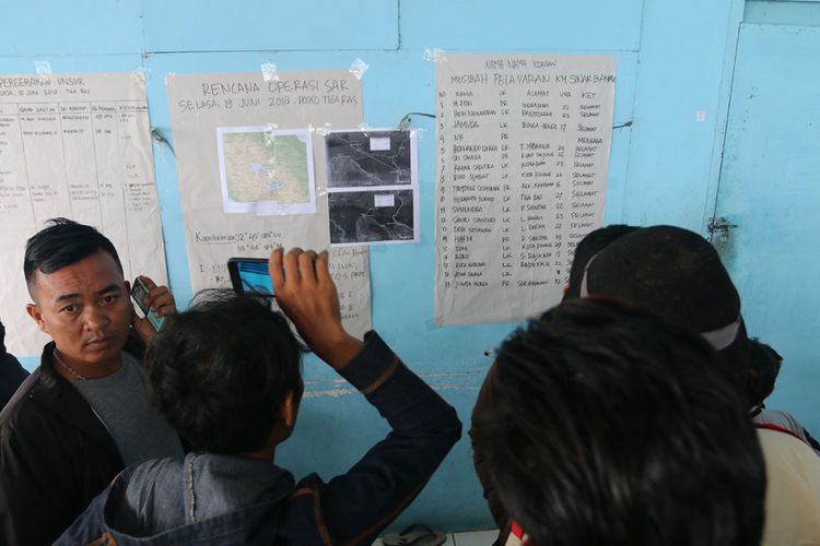 Anggota keluarga penumpang KM Sinar Bangun melihat daftar nama penumpang yang selamat, di posko Pelabuhan Tigaras, Danau Toba, Simalungun, Sumatera Utara, Selasa (19/6/2018). KM Sinar Bangun yang mengangkut ratusan penumpang tenggelam di Danau Toba pada Senin sore, dengan dilaporkan 1 penumpang tewas, belasan selamat, dan ratusan lainnya masih dalam proses pencarian.