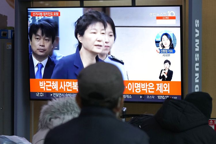 Orang-orang menonton layar TV yang menampilkan file gambar mantan Presiden Korea Selatan Park Geun-hye selama program berita di Stasiun Kereta Api Seoul di Seoul, Korea Selatan, Jumat, 24 Desember 2021. 