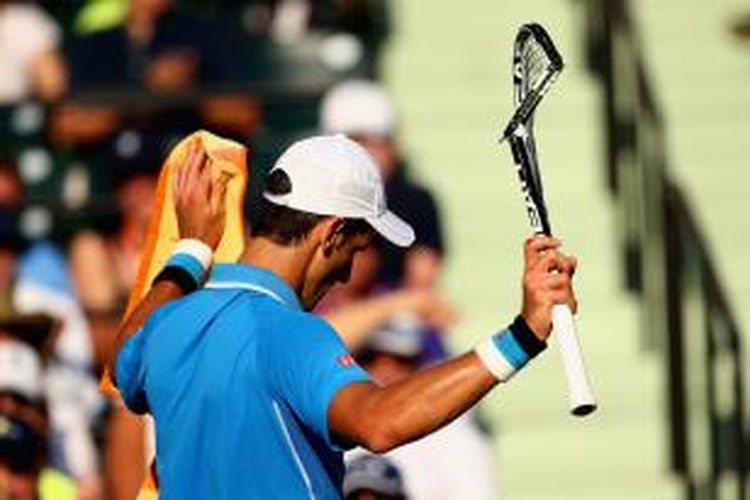 Petenis Serbia, Novak Djokovic, memegang raketnya yang rusak setelah dipukulkan ke lapangan saat melawan Alexandr Dolgopolov (Ukraina) pada babak keempat Miami Terbuka di Crandon Park Tennis Center, Selasa (31/3/2015).