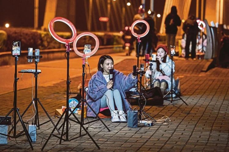Fenomena live di luar ruangan bernyanyi dan mengobrol dengan penonton melalui ponsel mereka di jembatan layang di Guilin, provinsi Guangxi, pada hari Senin. Gambar 