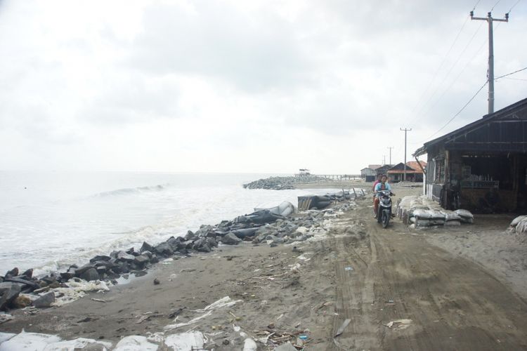 Seorang warga tengah mengendarai sepeda motor di jalan tepi Pantai Pisangan, Desa Cemara Jaya, Kecamatan Cibuaya, Kabupaten Karawang, Selasa (5/2/2019).
