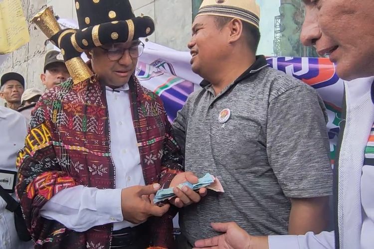Calon Presiden Nomor Urut 1 Anies Baswedan diberikan uang oleh relawannya saat berkampanye di Lapangan Istana Raja Ngajungal, Tapanuli Selatan, Sumatera Utara, Kamis (1/2/2024)