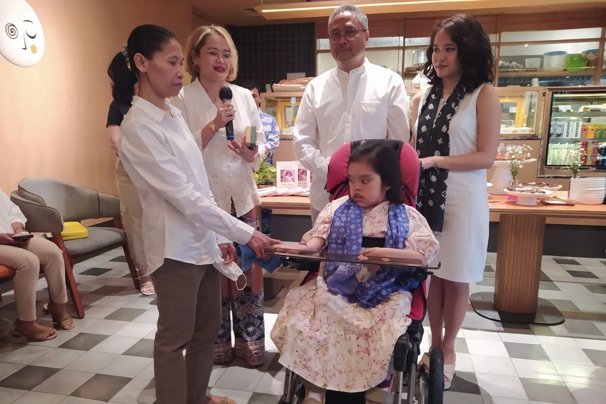 Penyandang cerebral palsy Teresa Olivia Purba (duduk di kursi roda) dalam peluncuran buku karyanya di Ashta Jakarta, Sabtu (20/5/2023), dikelilingi orang-orang terdekat pemberi support utama yakni (kiri ke kanan) Muji (pengasuh sejak kecil), Lisa Zen (ibu), Daniel Purba (ayah), dan Abigail Purba (kakak kandung).
