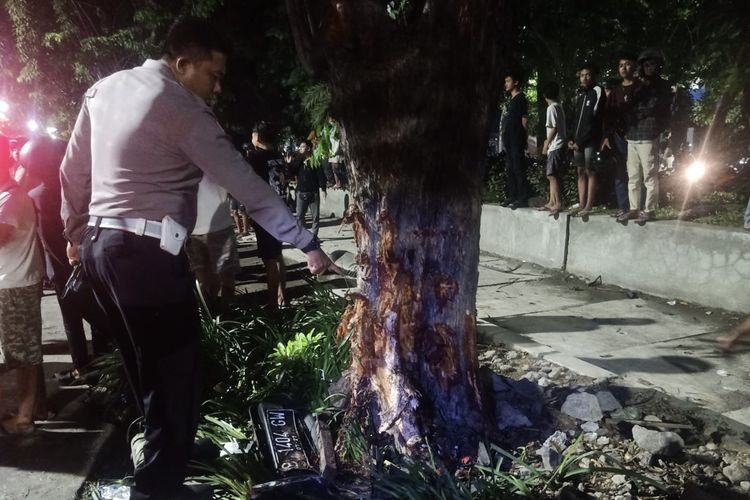 Polisi menunjuk pohon yang ditabrak mobil Ford di Surabaya, Minggu (8/12/2024).