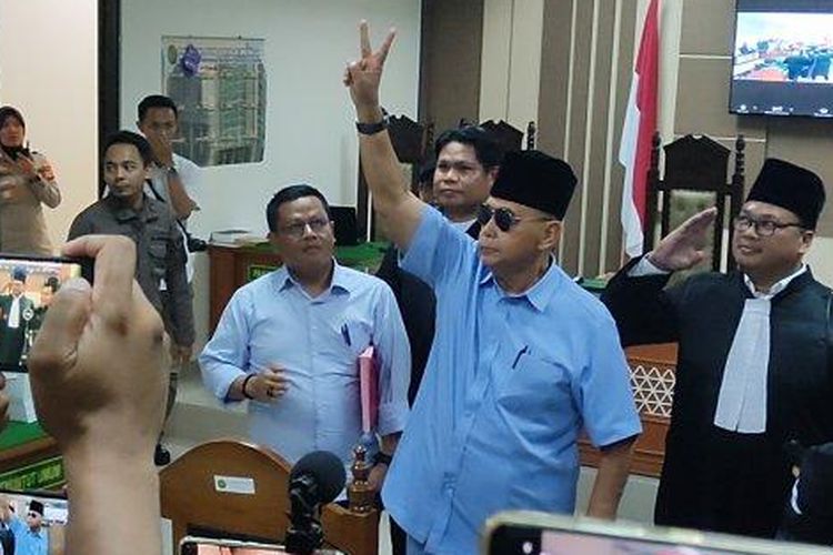 Terdakwa kasus pendodaan agama, Panji Gumilang, mengenakan setelan biru muda dan mengacungkan dua jari setelah dituntut JPU 1 tahun dan 6 bulan penjara di PN Indramayu, Kamis (22/2/2024). 