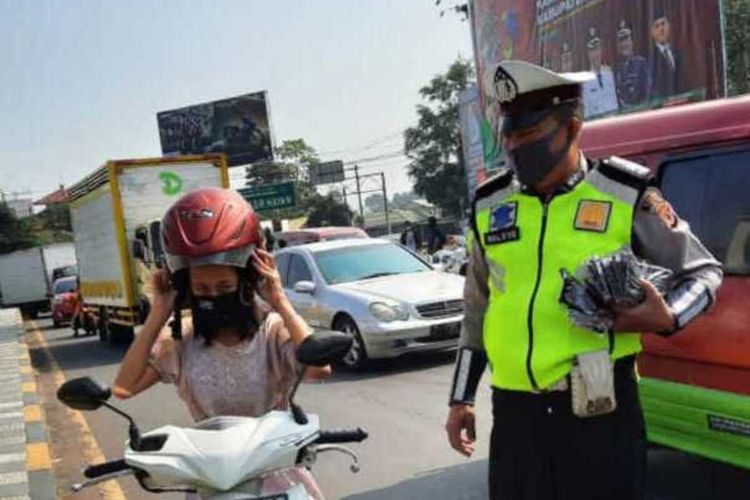 Seorang pengendara sepeda motor di Cianjur, Jawa Barat, yang kedapatan tidak memakai masker mendapat teguran dari polisi, untuk kemudian diberi masker untuk dipakai.