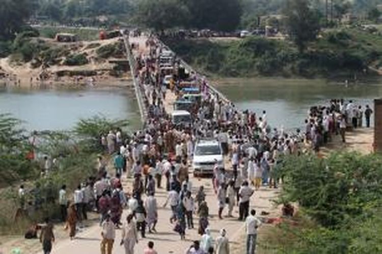 Polisi dan aparat pemerintah lain berkumpul di atas jembatan yang melintasi Sungai Sindh, setelah kepanikan yang membuat 115 orang peziarah Hindu tewas terinjak-injak atau tenggelam di sungai.