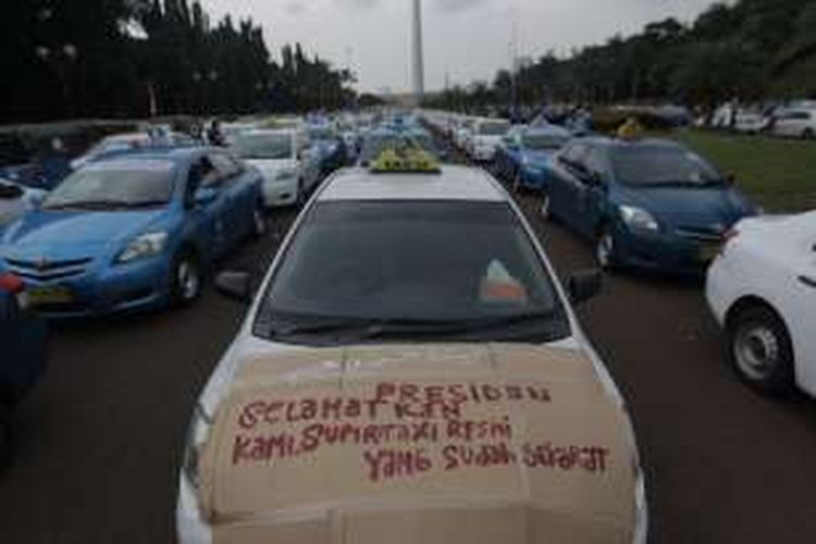 Gabungan sopir taksi dan bajaj memarkirkan taksi di kawasan Monumen Nasional saat melakukan aksi demonstrasi di Jakarta, Selasa (22/3/2016). Mereka menuntut pemerintah menutup angkutan umum berbasis online karena dianggap mematikan mata pencaharian mereka. KOMPAS.com / RODERICK ADRIAN MOZES