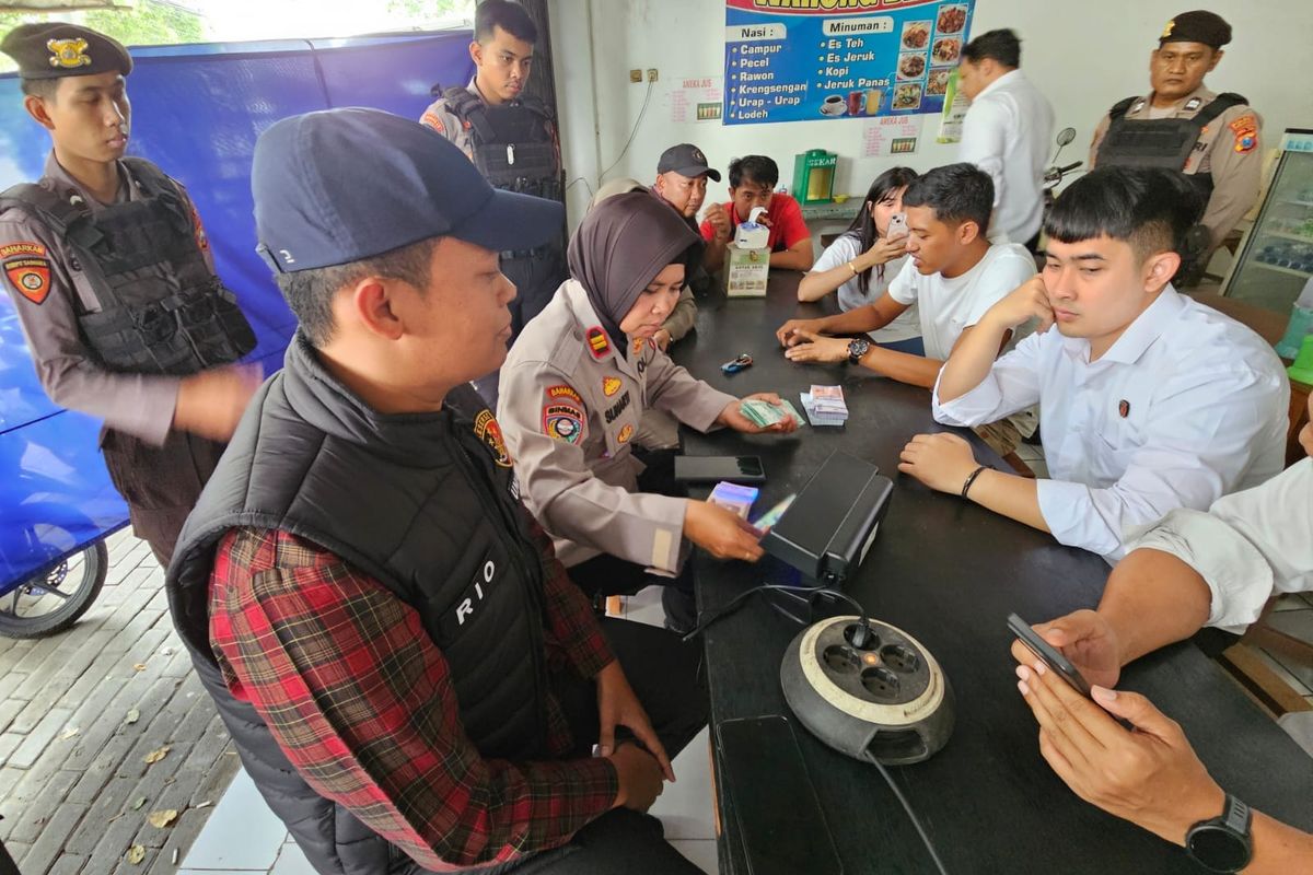 Aparat Kepolisian mengecek keaslian uang baru di tempat jasa tukar uang baru milik Wildan, pemuda yang mengaku punya uang baru senilai 2 miliar rupiah, Senin (24/03/2025) 