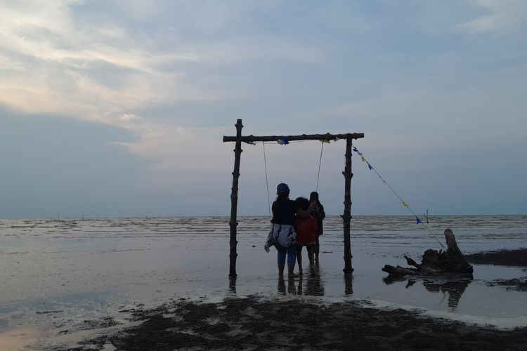  Salah seorang pengunjung menikmati ayunan di wisata pantai Pulau Arnavat Desa Surodadi, Kecamatan Sayung, Kabupaten Demak, Jawa Tengah, Rabu (27/12/2023) sore. (KOMPAS.COM/NUR ZAIDI)