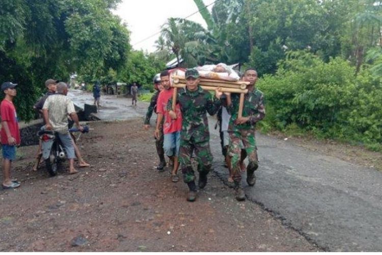 TNI dan warga menggotong seorang warga yang jadi korban banjir di wilayah Ile Ape, Kabupaten Lembata, Minggu 4 April 2021.
