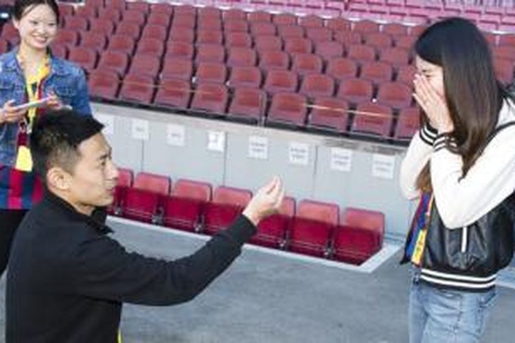 Seorang pria asal China, Liu Shutong (jongkok), melamar kekasihnya, Liu Panqiu (kanan), dalam sebuah tur di Stadion Camp Nou, Barcelona, Jumat (28/3/2014).