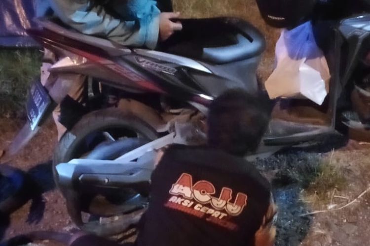 Relawan sedang menolong pengendara motor pada malam hari