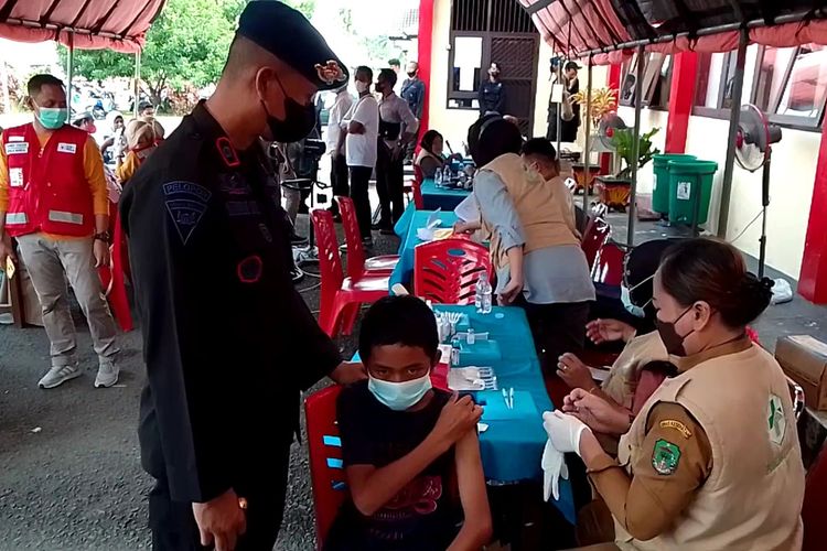 Yakson Nata (13) siswa kelas 1 Sekolah Menengah Pertama (SMP) di Dusun Pomotoa, Desa Sulaku,Kecamatan Rampi, Luwu Utara, Sulawesi Selatan didampingi Danyon D Pelopor saat mendapat suntikan vaksin covid-19 di Markas Brimob Baebunta, Rabu (29/12/2021)