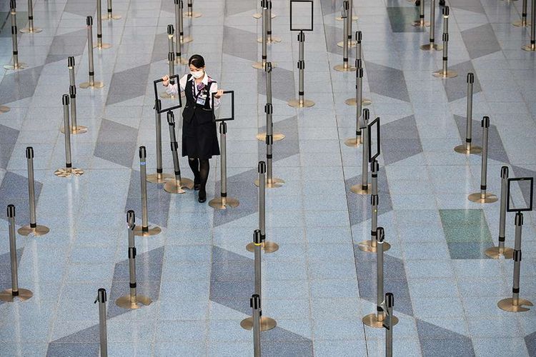 Seorang karyawan maskapai penerbangan mengenakan masker untuk mencegah penyebaran virus corona, saat beraktivitas di terminal keberangkatan Bandara Haneda, Tokyo, Minggu (10/3/2020). Kian merajalelanya virus corona (COVID-19) membuat sejumlah kawasan di berbagai belahan dunia yang selama ini dikenal ramai seketika berubah menjadi sepi.