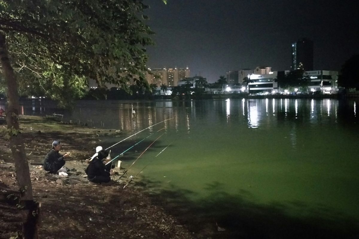 Masyarakat melakukan kegiatan memancing sembari menyambut kedatangan tahun 2018 di tepi Danau Sunter, Jakarta Utara, Minggu (31/12/2017). 