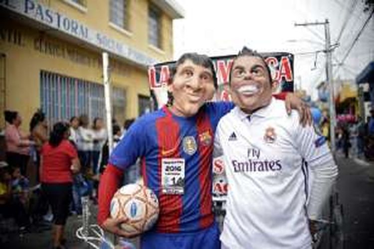 Dua orang yang memakai topeng serta kostum Lionel Messi dan Cristiano Ronaldo memeriahkan karnaval All Saints Day di Guatemala pada awal November 2016. 