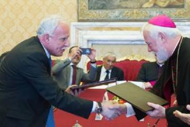 Menteri Luar Negeri Vatikan Paul Gallagher, kanan, dan Menteri Luar Negeri Palestina, Riad al-Malki, berjabat tangan setelah menandatangani perjanjian, tentang operasi gereja di Tanah Suci di bawah pengawasan Palestina, di Vatikan, 26 Juni 2015.