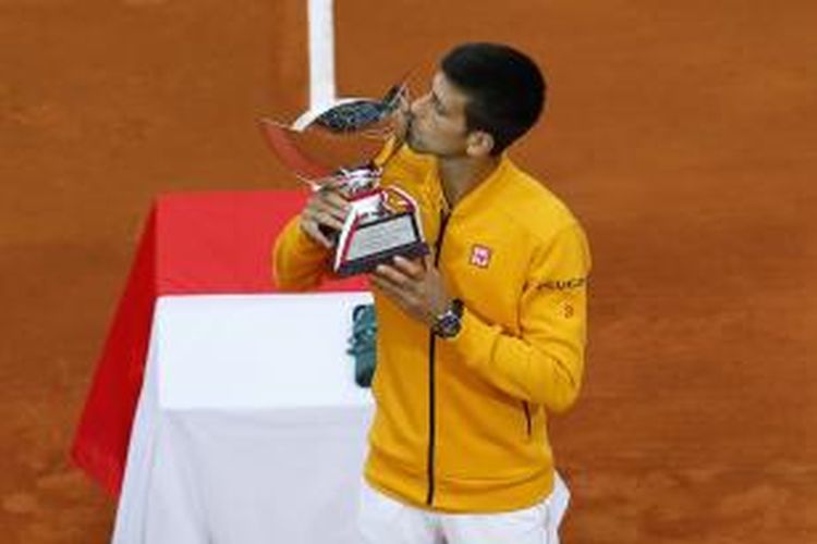 Peteins Serbia, Novak Djokovic, mencium trofi juara Monte Carlo Masters yang didapat setelah mengalahkan Tomas Bedych (Ceko) pada laga final, Minggu (19/4/2015). Djokovic menang 7-5, 4-6, 6-3.