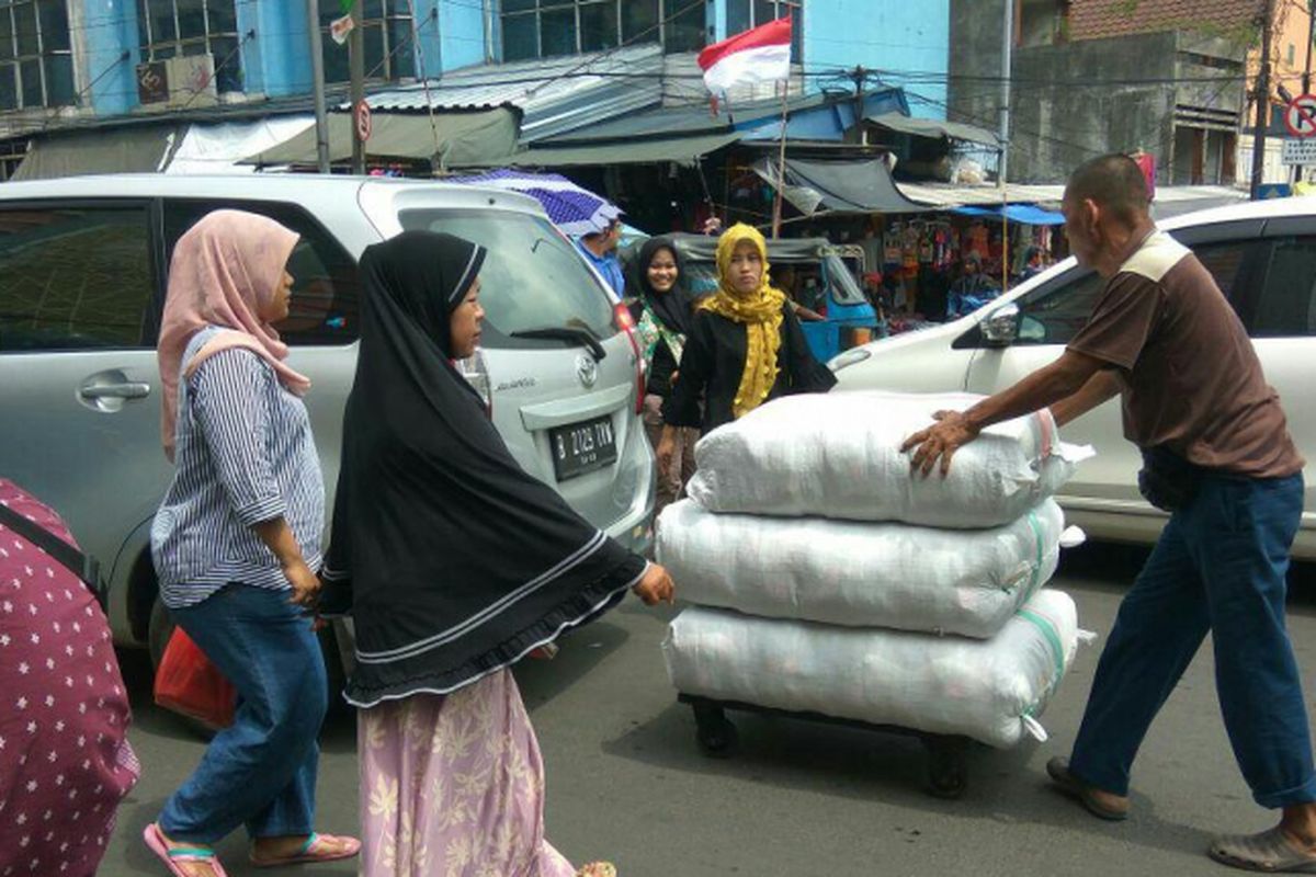 Para porter di kawasan Pasar Tanah Abang berjibaku dengan kendaraan untuk mengantarkan barang ke kios ekspedisi, Senin (12/3/2018).