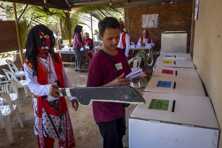 Petugas KPPS yang mengenakan baju trasisional pemain kuda lumping membantu warga memasukkan kertas suara di TPS 21 Kelurahan Tanjung Piayu, Sungai Beduk, Batam, Kepulauan Riau, Rabu (17/4/2019). Aksi tersebut dilakukan sebagai bentuk antusiasme warga dalam memeriahkan pesta demokrasi serta untuk menarik minat masyarakat untuk menggunakan hak pilihnya. ANTARA FOTO/M N Kanwa/aww.