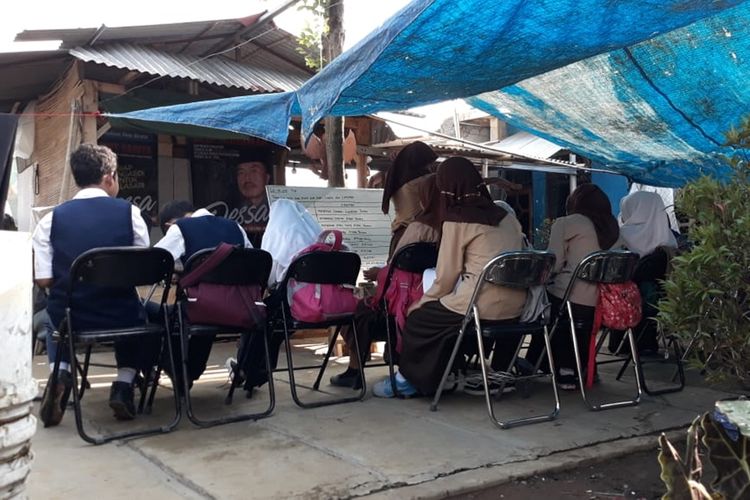 Sejumlah siswa SMP TB 911 yang menginduk SMP 1 Cijeruk melakukan kegiatan belajar mengajar (KBM) di halaman rumah menggunakan terpal, milik Cucu Sumiati (39) selaku tenaga pengajar dan relawan pendidikan, Kamis (29/8/2019).