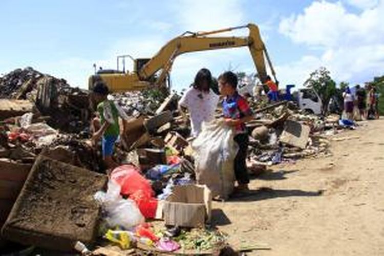 Beberapa anak sedang memilah sampah banjir bandang yang dibuang di TPA Sumompo Manado. Mereka kemudian menjual kembali sampah yang masih bisa didaur ulang tersebut.