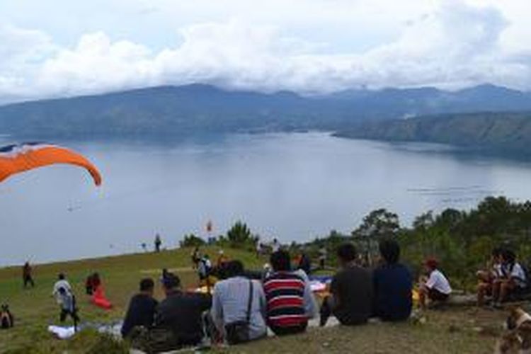 Penduduk menonton atraksi paralayang di Bukit Siulakhosa, Pulau Samosir, Sumatera Utara. Paralayang merupakan rangkaian kegiatan Festival Danau Toba 2013 yang digelar 8–14 September 2013.