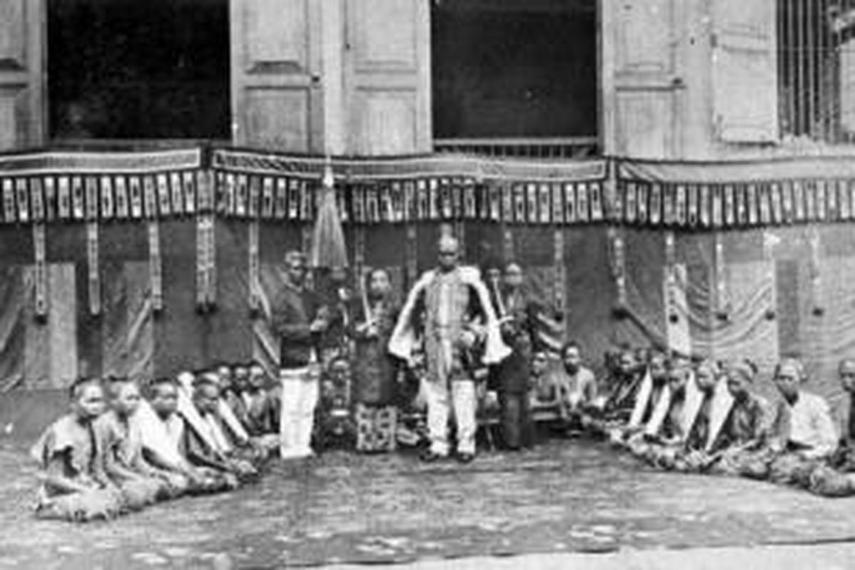 Sultan Aji Muhammad Sulaiman dan para pengiringnya di depan kedaton, Tenggarong. Sang Sultan bertakhta di Kesultanan Kutai pada periode 1850-1899. Pada 1879, Carl Bock, seorang naturalis dan penjelajah asal Norwegia, pernah berbincang dengannya tentang 