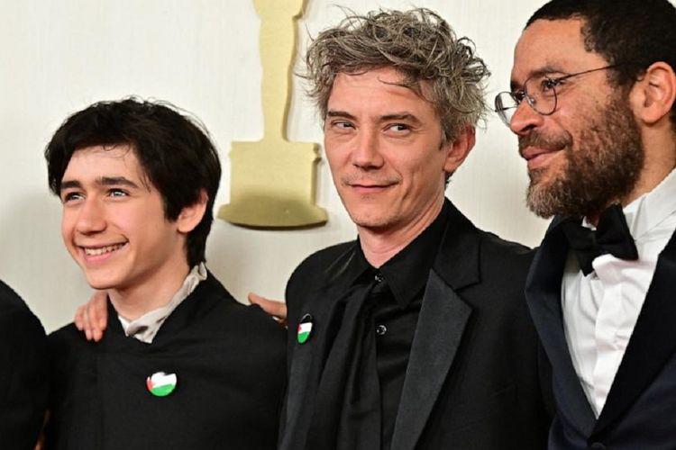 Aktor asal Perancis Milo Machado-Graner (kiri) dan Swann Arlaud (tengah) menyematkan pin bendera Palestina pada jas mereka saat menghadiri Academy Awards ke-96 atau Oscar 2024 di Hollywood, Minggu (10/3/2024).