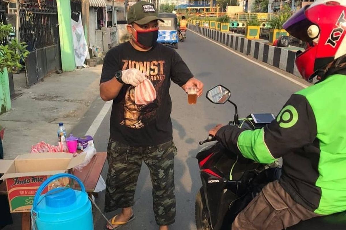 Seorang warga Kemayoran, Jakarta Pusat, membagikan sarapan pagi gratis untuk supir ojek online dan pengemudi bajaj di kawasan Jl. Bendungan Jago 
