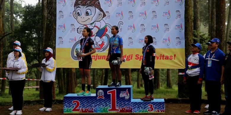 Peraih medali emas balap sepeda cross country putri PON XIX Jawa Barat 2016, Kusmawati Yazid (tengah), bediri di atas podium setelah penyerahan medali. Pebalap sepeda Riau, Wilhemina (kiri) dan Novianan (kanan), finis di urutan pertama dan kedua. Balap sepeda cross country putri berlangsung di Cikole, Lembang, Senin (19/9/2016).