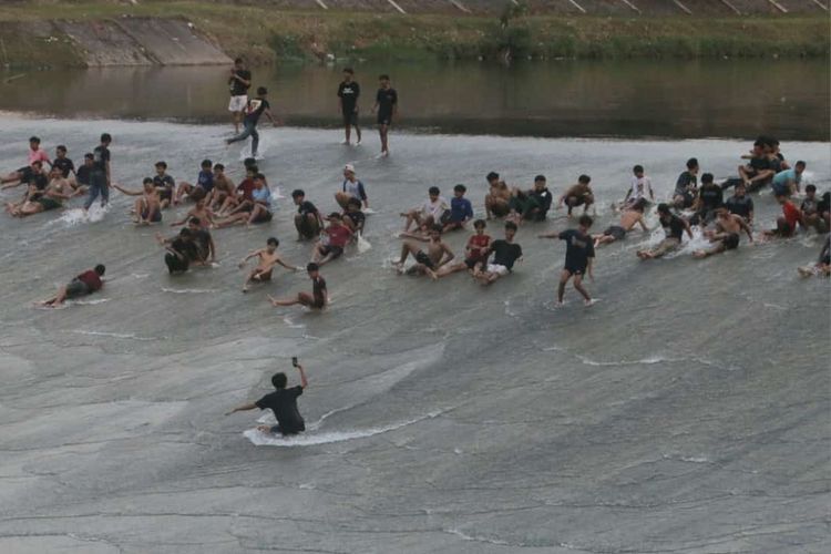 Pemandangan banyaknya anak-anak dan remaja yang main seluncuran di pintu air bendungan Pleret Banjirkanal Barat (BKB) Kota Semarang, baru-baru ini.