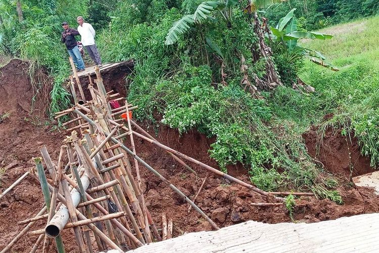 Warga memerhatikan kondisi jalan penghubung antar desa di Cianjur, Jawa Barat yang terputus akibat lomgsor, Jumat (17/2/2023). Kejadian tersebut dipicu curah hujan dan retakan badan jalan akibat gempa M5.6 beberapa waktu lalu.