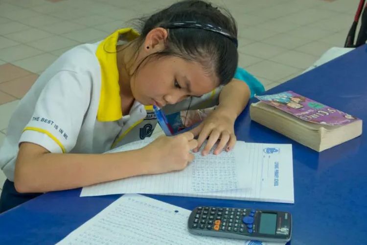 Seorang anak Singapura sedang mengerjakan soal matematika.