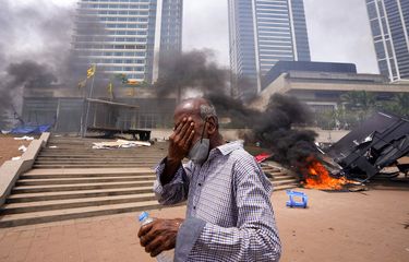 Seorang pria Sri Lanka bereaksi terhadap gas air mata saat dia berjalan melewati lokasi protes anti-pemerintah yang dirusak di luar kantor presiden di Kolombo, Sri Lanka, Senin, 9 Mei 2022. 