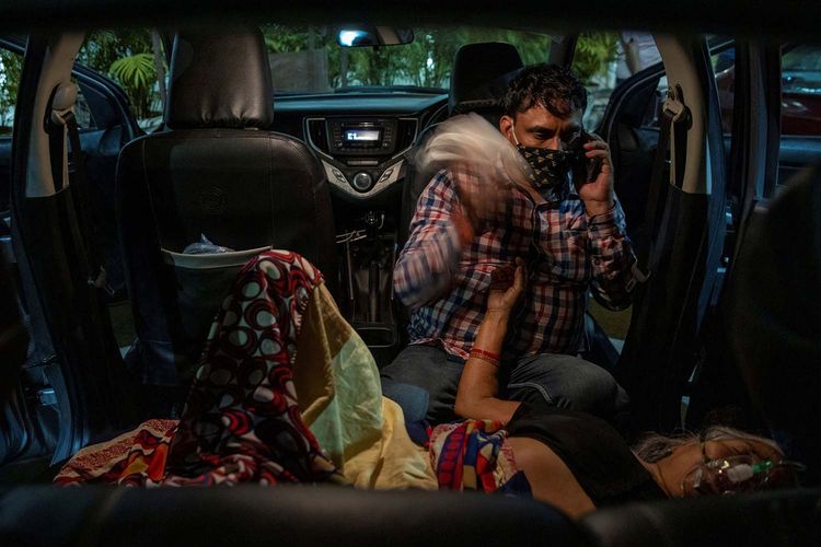 Manoj Kumar duduk di sebelah ibunya Vidhya Devi, yang menderita kesulitan bernapas ketika menerima bantuan oksigen secara gratis di dalam mobilnya d Gurudwara (kuil Sikh), saat mewabahnya virus corona (COVID-19), di Ghaziabad, India, Sabtu (24/4/2021). 