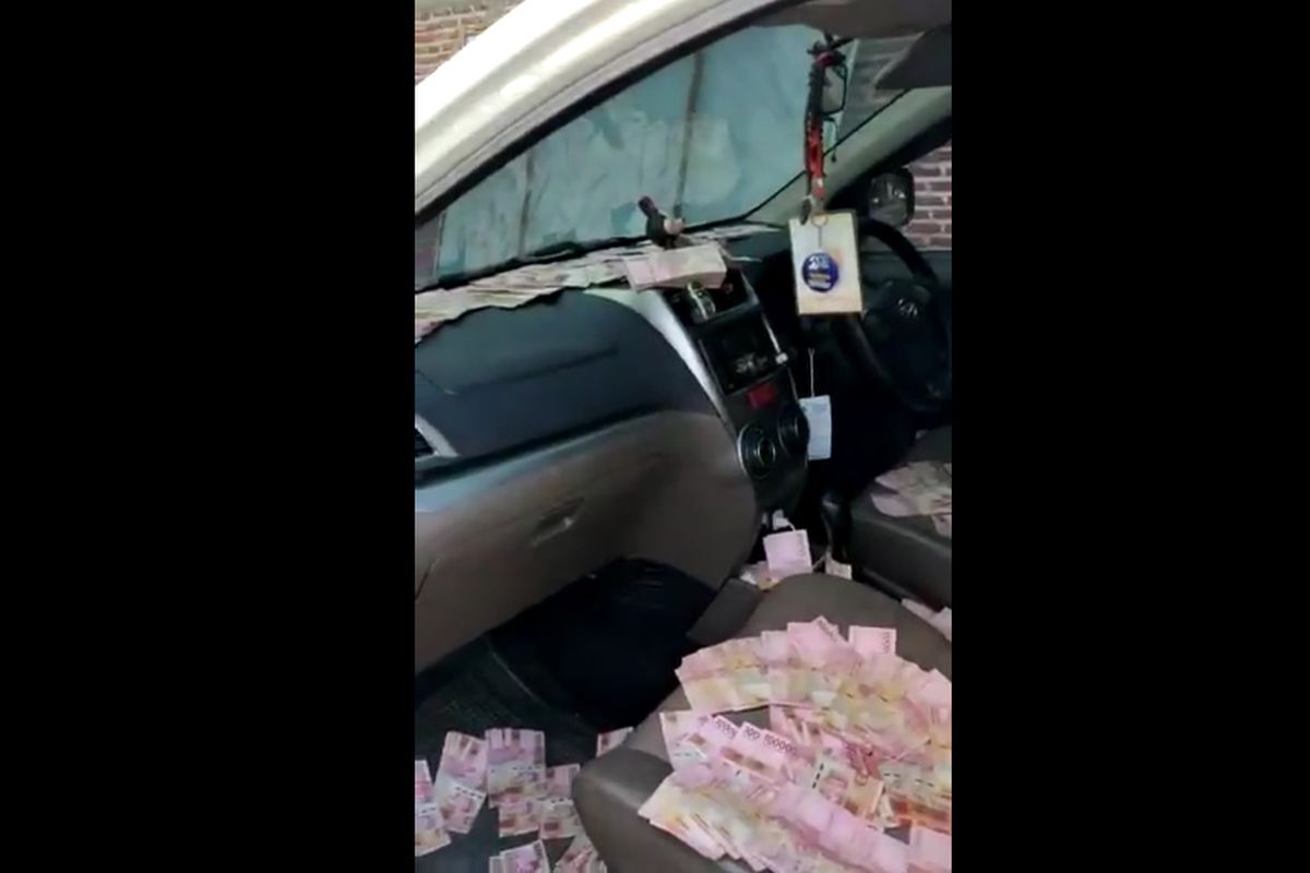 A screen grab of video footage showing scattered money inside a car that allegedly belongs to a supporter of candidate pair of regional elections in Mojokerto regency in East Java, Indonesia. 