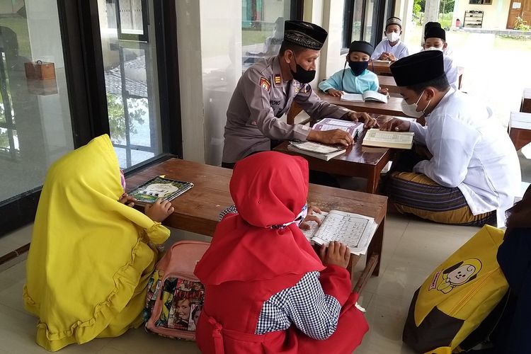 BACA Al QURAN—Pengasuh Pondok Pesantren Abdul Raham Bin Auf, AKP Surono (Kapolsek Eromoko-Wonogiri) menyimak bacaan Al Quran yang dibaca salah satu santrinya, Sabtu (30/10/2021).