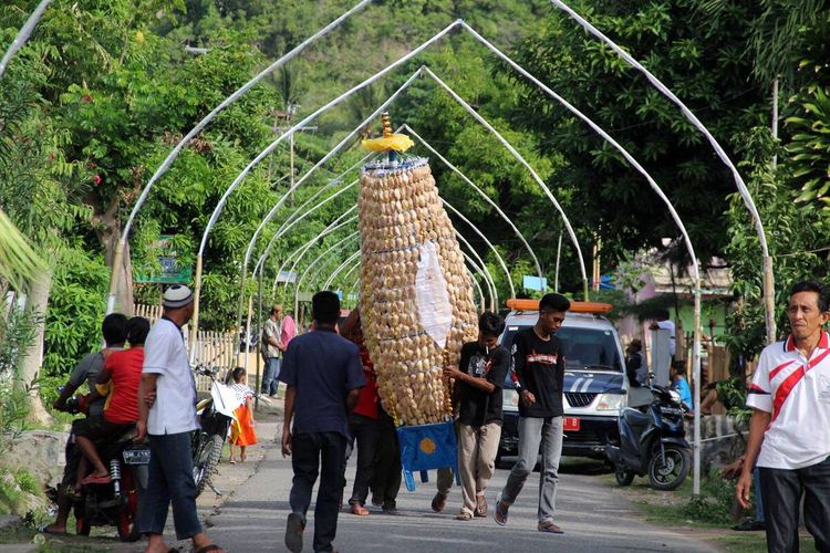Sejumlah warga desa membawa kue walima dalam usungan ke masjid dengan susah payah. Kue-kue ini akan dibagikan ke pelantun dikili dan masyarakat yang hadir dalam perayaan Maulid Nabi Muhammad (Walima).