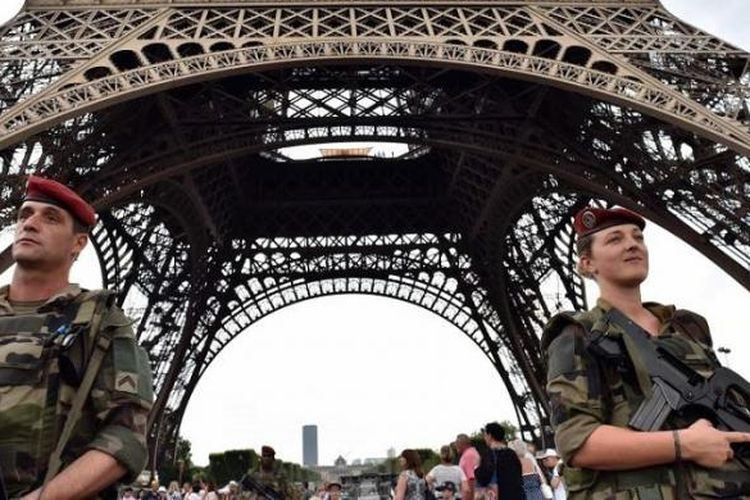 Tentara berjaga di kaki Menara Eiffel, Paris, Perancis. Menara ini berada di sebuah taman yang luas, yang disebut Champs de Mars. 