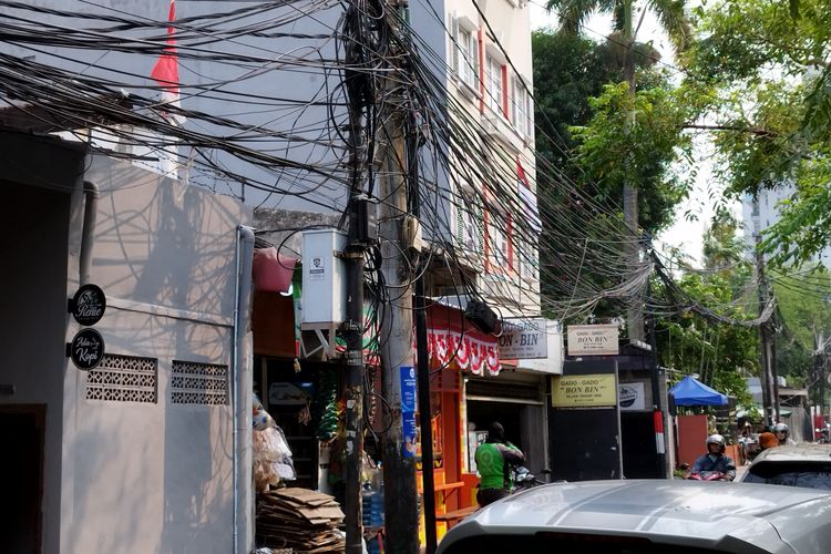 Tiang listrik dengan kabel fiber optik yang menggantung berantakan di Jalan Cikini IV, Menteng, Jakarta Pusat, Senin (7/8/2023).