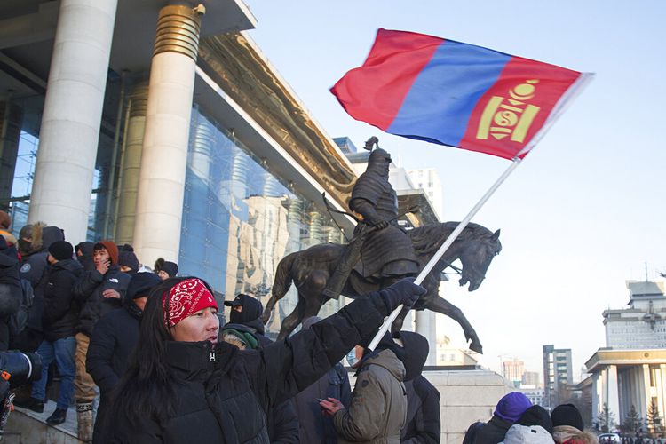 Seorang pengunjuk rasa mengibarkan bendera nasional Mongolia saat pengunjuk rasa berkumpul di tangga Istana Negara di Ulaanbaatar di Mongolia pada Senin, 5 Desember 2022.