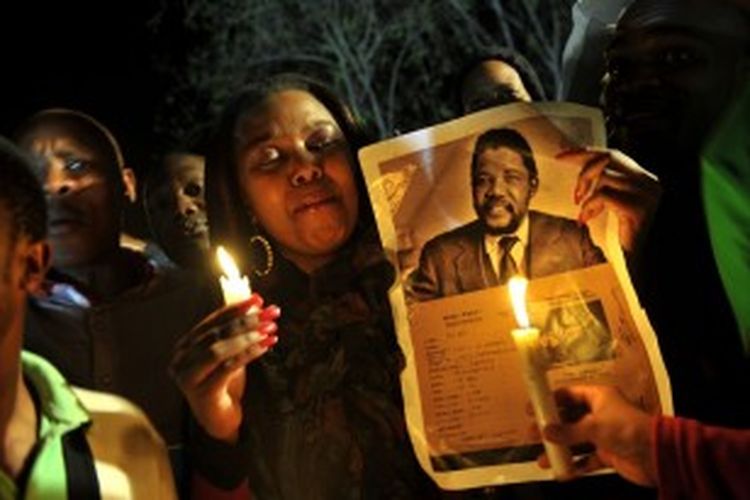 Warga Afrika Selatan di Pretoria sambil menyalakan lilin dan membawa foto Nelson Mandela muda, mendoakan kesehatan tokoh pejuang anti-apartheid yang kini masih terbaring lemah di rumah sakit.