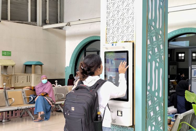 Potrait calon penumpang sedang mencetak tiket di mesin pencetak tiket Stasiun Pasar Senen, Senin (1/12/2025). 