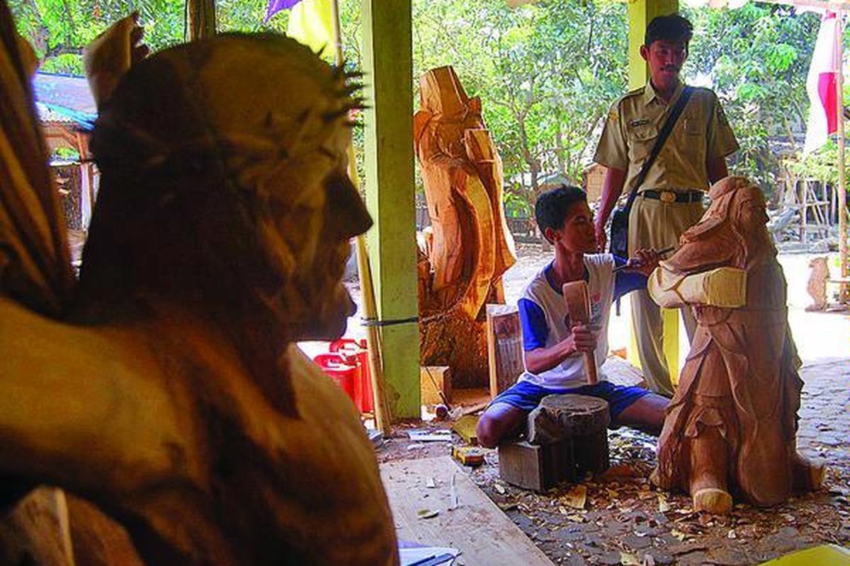 Seorang perangkat Desa Mulyoharjo sedang mendampingi pengukir mula yang tengah nyantrik atau magang mendalami seni ukir di UD Mblakang Gunung, Desa Mulyoharjo, Kecamatan Jepara, Kabupaten Jepara, Jawa Tengah, Senin (22/8).